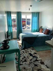 Aquamarine Suites في كودياك: غرفة نوم بسرير والستائر الزرقاء وطاولة