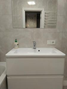 lavabo blanco en el baño con espejo en Апартаменти Люкс2 en Khmelʼnytsʼkyy