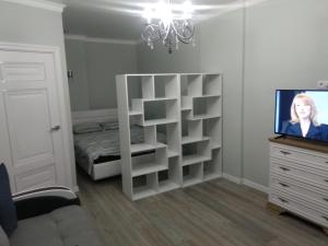 a bedroom with a white book shelf and a tv at Апартаменти Люкс2 in Khmelʼnytsʼkyy