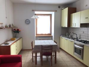 une cuisine avec une table et une cuisine avec des placards jaunes dans l'établissement Appartamento a Spinazzeda cuore di Cles, à Cles