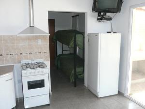 a kitchen with a white refrigerator and a stove at Cabañas Tintihuasi in Villa de Las Rosas