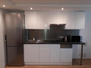 a kitchen with white cabinets and a stainless steel refrigerator at Cosy flat in the quiet area with own garden, free parking and direct public transport link to the centre in Vienna