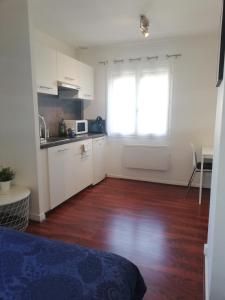 uma cozinha com armários brancos e uma janela num quarto em L4 - Green and cosy flat close Paris - WIFI & NETFLIX em Longjumeau