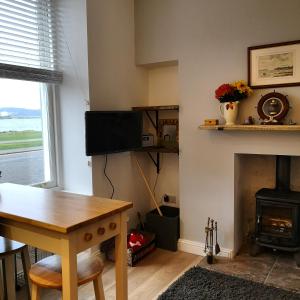 a living room with a table and a fireplace at Beside the Bay in Millport