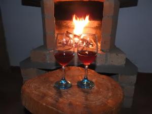 two glasses of wine sitting on a table in front of a fireplace at Posada Chaska in San Agustín