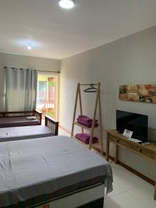 a bedroom with a bed and a television and a desk at Hotel Zona Sul in São Gabriel