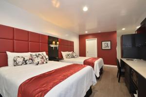 two beds in a hotel room with red walls at Legend Hotel Hollywood in Los Angeles