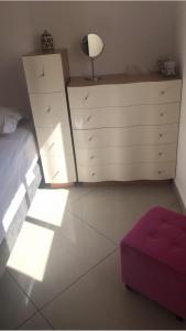 a bedroom with a bed and a dresser with a purple ottoman at CHAMBRES D’HÔTES EILAT in Eilat