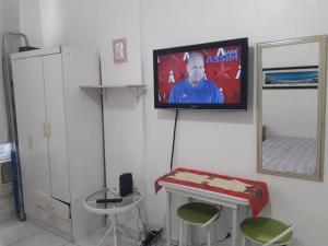 a room with a tv on a wall with a table and stool at Studio Santa Clara in Rio de Janeiro