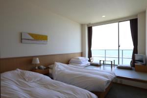 ein Hotelzimmer mit 2 Betten und einem Balkon in der Unterkunft Bayside Square Kaike Hotel in Yonago
