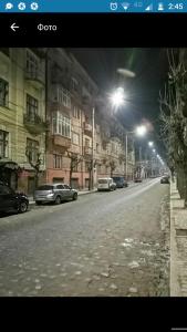 a city street at night with cars parked on the road at Apartmen28juni in Chernivtsi