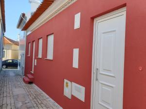 a red building with a white door on a street at Beco's House - Suits in Ílhavo