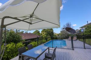 una terraza con mesa, sombrilla y piscina en Swimming Pool Holiday Villa, en Auckland