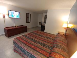 a hotel room with a bed and a flat screen tv at Relax Inn Silver Springs in Silver Springs