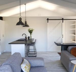 uma sala de estar com um sofá e uma cozinha com um balcão em Garden View Cottage em Carterton