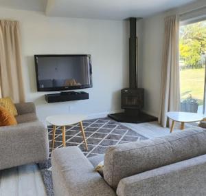 a living room with a couch and a tv at Garden View Cottage in Carterton