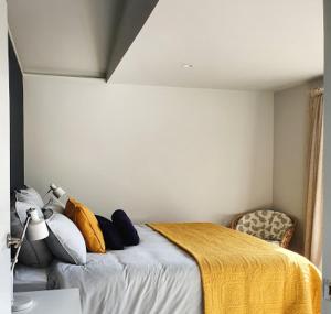 a bedroom with a bed with a yellow blanket on it at Garden View Cottage in Carterton