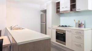 a kitchen with a stove top oven and a microwave at Oaks Brisbane on Charlotte Suites in Brisbane