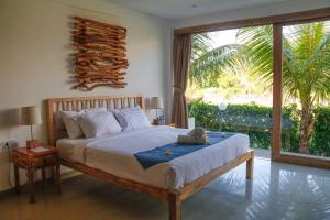 a bedroom with a bed and a large window at D'sawah Villa in Tanah Lot +77 photos