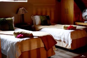 two beds in a hotel room with flowers on them at Kududu Guest House in Addo