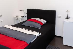 Zimmervermietung Dietzenbach في ديتسنباخ: غرفة نوم بسرير أسود ومخدات حمراء وبيضاء