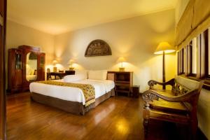 a bedroom with a bed and a table and a chair at Laras Asri Resort & Spa in Salatiga