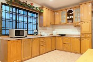 a kitchen with wooden cabinets and a microwave at REBECS 12Pax@TebrauCity/Ikea/Toppen/Aeon in Johor Bahru
