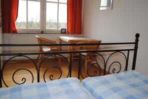 a bedroom with a bed and a table and windows at Hof Faasel - Bauernhofurlaub an der Ostsee in Grömitz