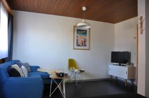 a living room with a blue couch and a tv at Chalet Bietschhorn Rosswald in Termen