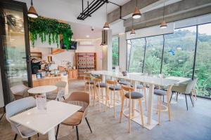 a restaurant with white tables and chairs and large windows at Passion Resort Kiriwong in Kiriwong