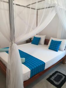 sypialnia z łóżkiem z niebieskimi poduszkami w obiekcie Lasindu Guest w mieście Ahangama