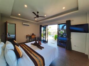 a bedroom with a large bed with a ceiling fan at Baan Sawan Samui Resort in Chaweng Noi Beach