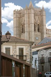 un edificio con una torre con un reloj. en Apartamentos turisticos Avila La Catedral, en Ávila