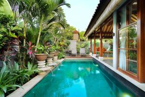 a swimming pool in front of a house with plants at Aradhana Villas by Ekosistem in Canggu