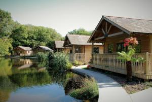 a log cabin with a pond in front of it at Canada Lodge and Lake in Creigiau