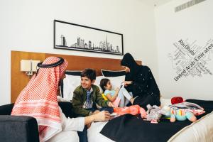 a family sitting on a bed playing with toys at TRYP by Wyndham Dubai in Dubai