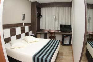 una habitación de hotel con una cama y un televisor en Hotel Maestro Express, en Francisco Beltrão
