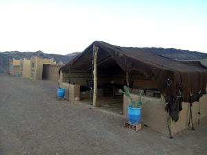 a tent with a table and blue buckets under it at Auberge Camping Tafraoute Montagnes in Tafraoute Sidi Ali