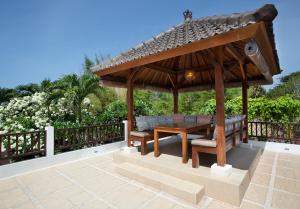 a wooden gazebo with a wooden table and chairs at Puri Temple Villa in Canggu