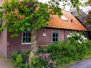 een rood bakstenen huis met een oranje dak bij De Windroos | Atelier Aan Zee in Groet