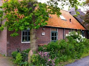 una casa de ladrillo rojo con techo naranja en De Windroos | Atelier Aan Zee, en Groet