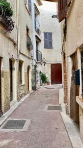 an empty alley with buildings and a red door at Charmant studio vieil Antibes in Antibes