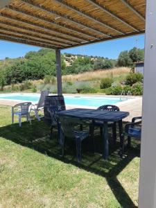a table and chairs under awning next to a pool at Podere Erba appartamento con piscina in Cinigiano