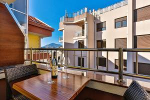 a wooden table with wine glasses on a balcony at Apartmani Luka - Vila Brzulovic in Rafailovici