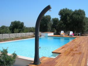 a swimming pool with a black pole next to a wooden deck at Masseria Montecchie in Ceglie Messapica