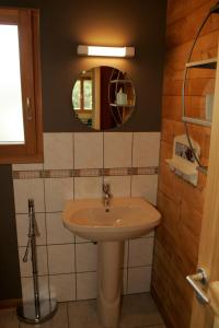 ein Bad mit einem Waschbecken und einem Spiegel in der Unterkunft Les Myrtilles in Le Bonhomme