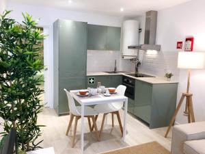 a kitchen with green cabinets and a white table and chairs at Casas Madre de Deus in Évora