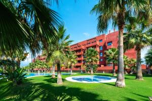 a hotel with palm trees in front of a building at Ático de Lujo Playa Granada, BLUE&GREEN in Motril
