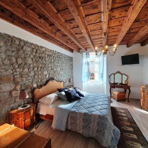 チヴィダーレ・デル・フリウーリにあるB&B Domus iuliiの石壁のベッドルーム1室(ベッド1台付)