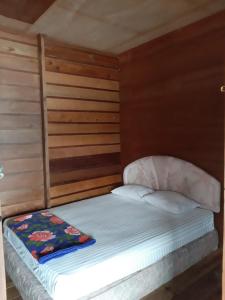 Cama pequeña en habitación con paredes de madera en Beach Guest House, en Maninjau